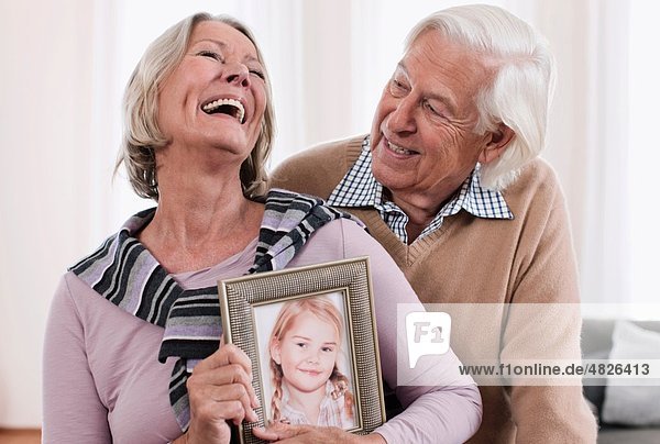 Germany  Wakendorf  Grandparents holding granddaughter photograph