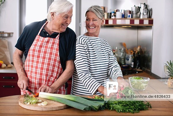 Germany  Wakendorf  Senior couple cutting vegetables in the kitchen