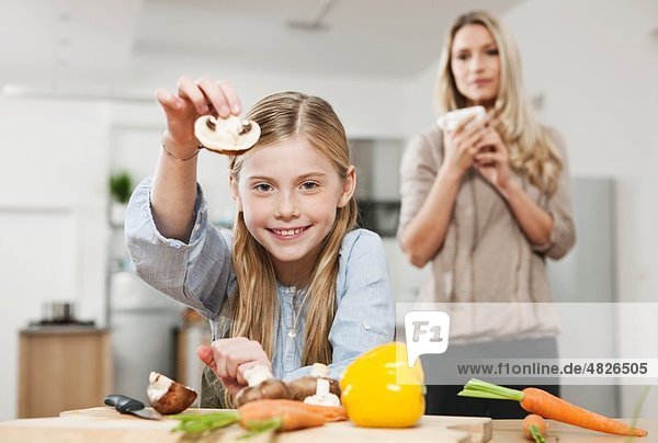 Deutschland    Tochter schneidet Gemüse mit Mutter im Hintergrund