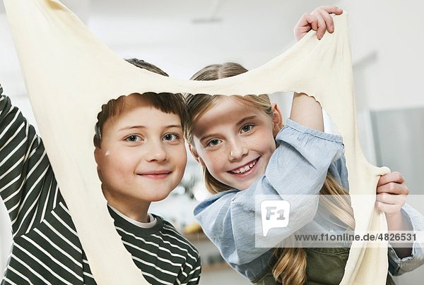 Mädchen und Junge spielen mit dem Teigblatt