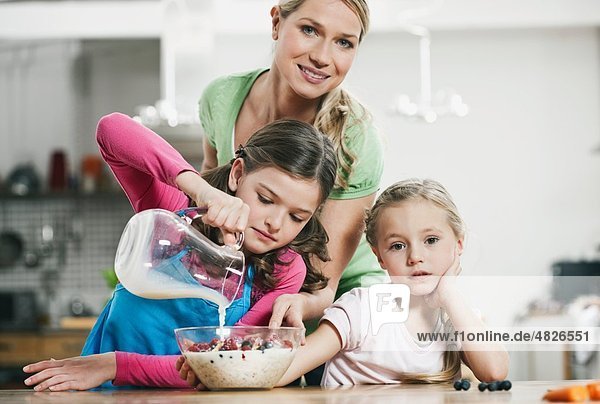 Deutschland    Mutter und Kinder bereiten Müsli zum Frühstück vor