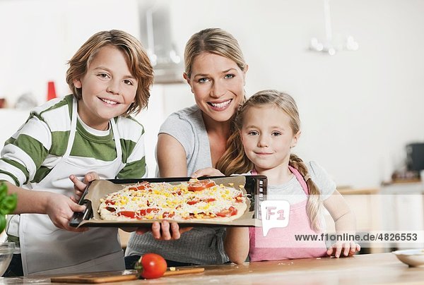 Germany    Mother and children making pizza in kitchen