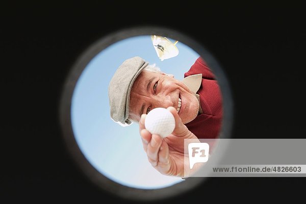 Italien  Kastelruth  reifer Mann mit Golfball im Loch