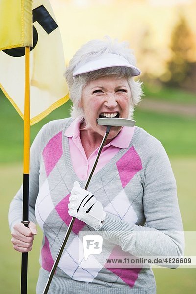 Italien  Kastelruth  Reife Frau mit Golfschläger und Golfflagge auf dem Golfplatz