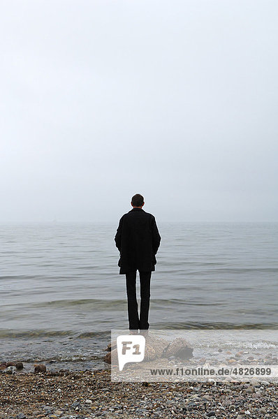 Young man standing in inclement weather on the Baltic Sea  Gross Schwansee  Mecklenburg-Western Pomerania  Germany  Europe