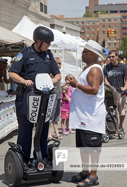 Eine Polizist der Wayne State University auf einem Segway Personal Transporter im Gespräch mit einem Mann auf der Straße bei einem Festival  Detroit  Michigan  USA