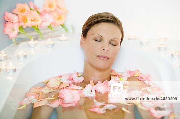 Junge Frau im Bad mit Blütenblättern