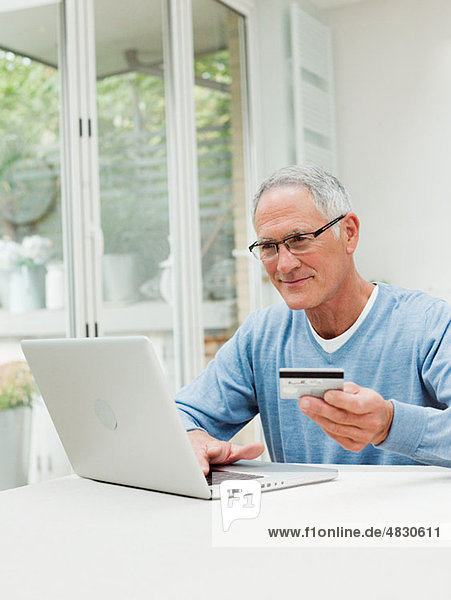 Senior Mann mit Laptop und Kreditkarte