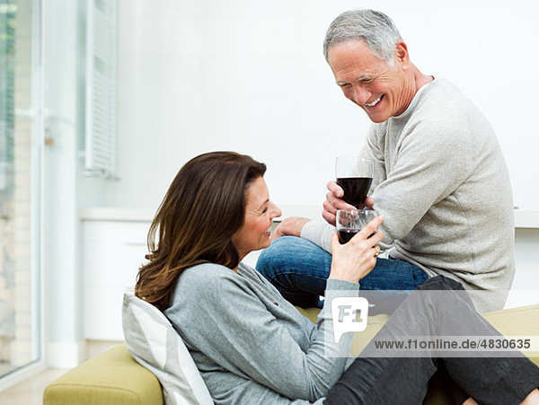 Erwachsenes Paar auf dem Sofa sitzend mit Wein