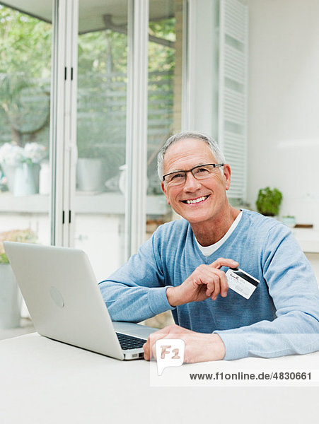 Senior Mann mit Laptop und Kreditkarte