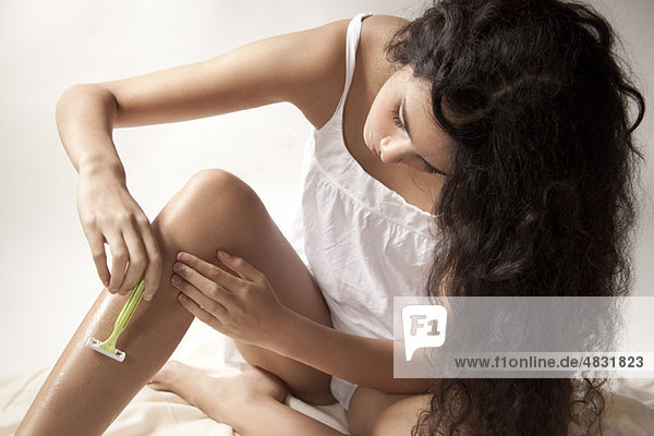 Young woman shaving legs