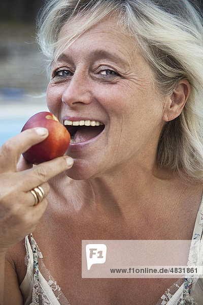 Reife Frau beißt in den Apfel