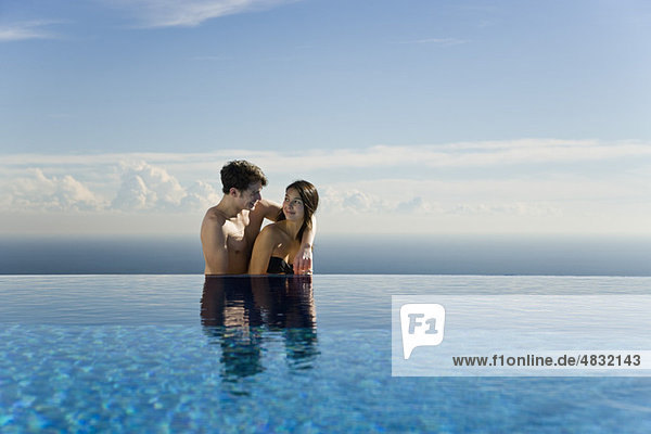 Couple relaxing together next to infinity pool