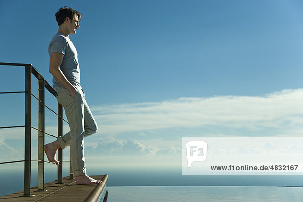 Man leaning against railing  looking at view