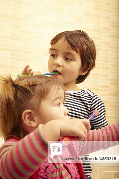 Junge und Mädchen beim Zähneputzen im Bad
