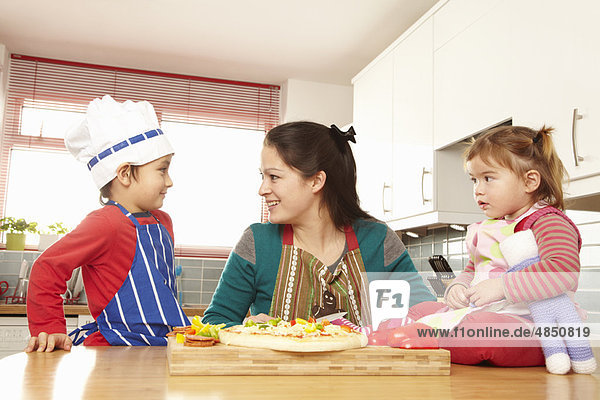 Mother cooking with children in kitchen
