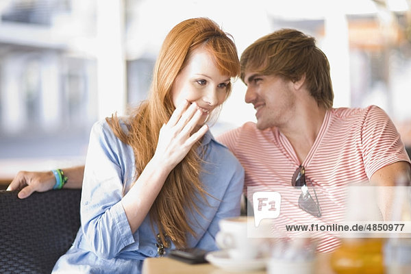 Junges lachendes Paar bei einem Kaffee