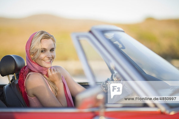 Blond woman with red scarf in cabriolet