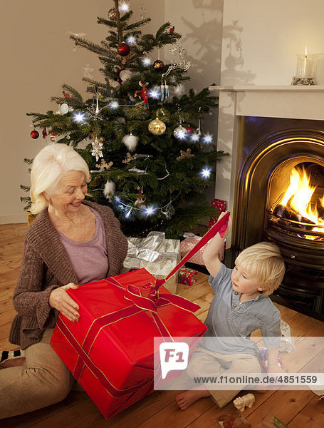 Enkel öffnet ein Geschenk mit seiner Großmutter
