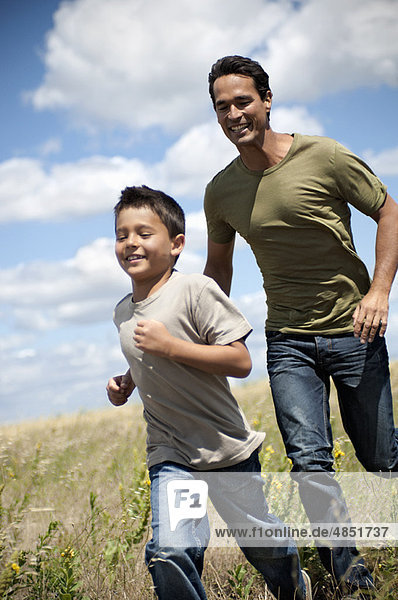 Vater und Sohn laufen durch ein Feld.