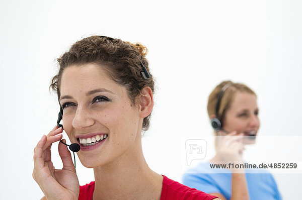 Two women with headsets in office