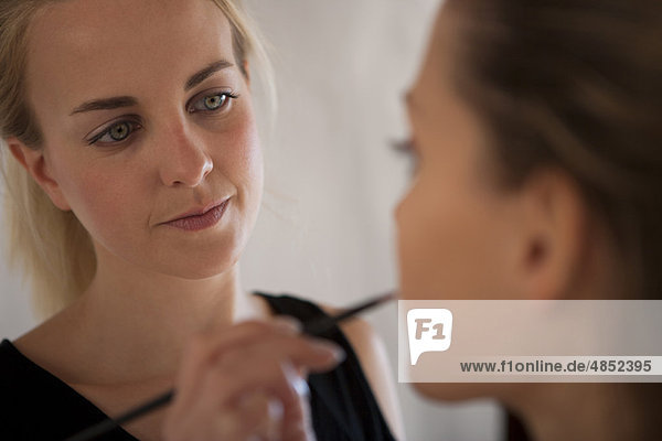Make-up Artist beim Auftragen von Lippenstift auf das Modell mit Lippenpinsel und Mund