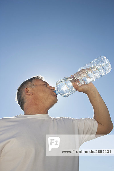 Erwachsener Mann trinkt Wasser aus der Flasche