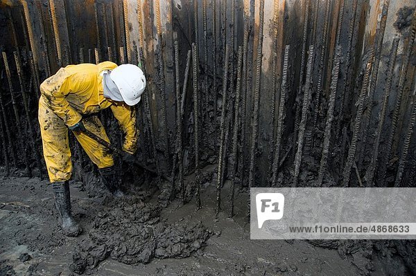 Rotterdam  Netherlands. Young man removing river mud from an underground construction site  after drainage of the pit.