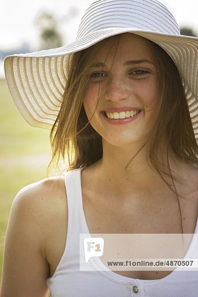 Fröhliche junge Frau mit Hut im Freien