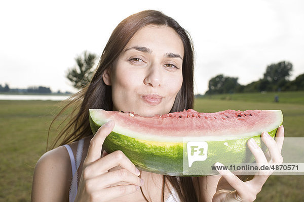 Junge Frau isst eine Melone im Freien