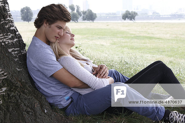 Young couple embracing at tree trunk