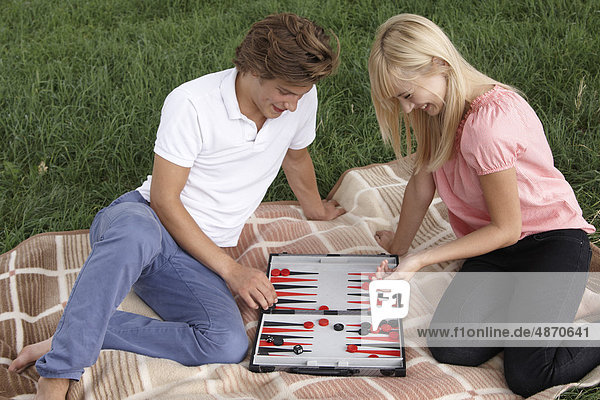 Junges Paar spielt Backgammon im Freien