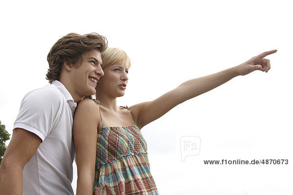 Junge Frau zeigt ihrem Freund etwas im Freien