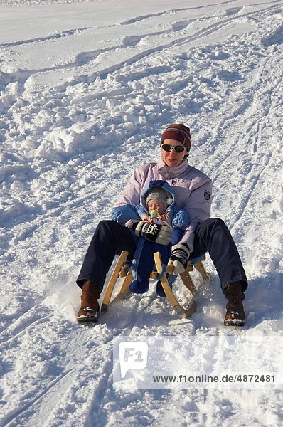 mother tobogganing with child