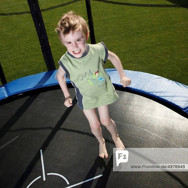 little boy jumping on trampoline in garden
