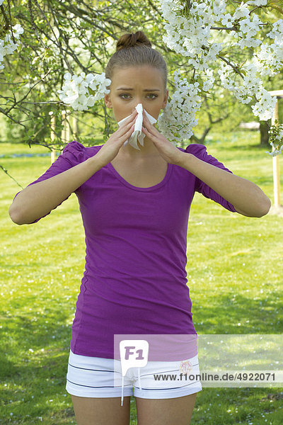 Young woman blowing nose
