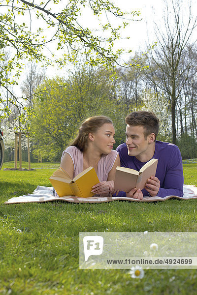 Young couple reading on a meadow