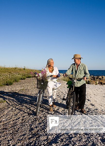 Mature couple riding bicycle on beach