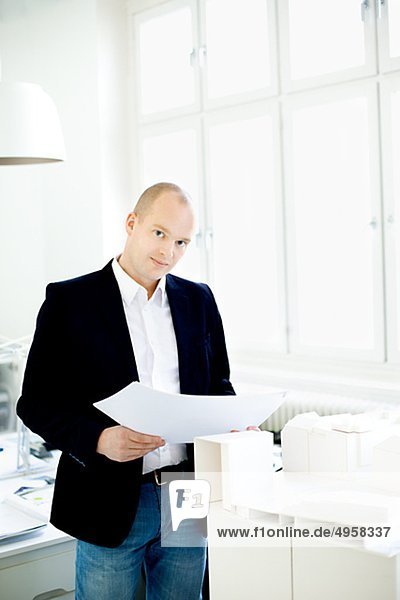 Man standing by model houses in office