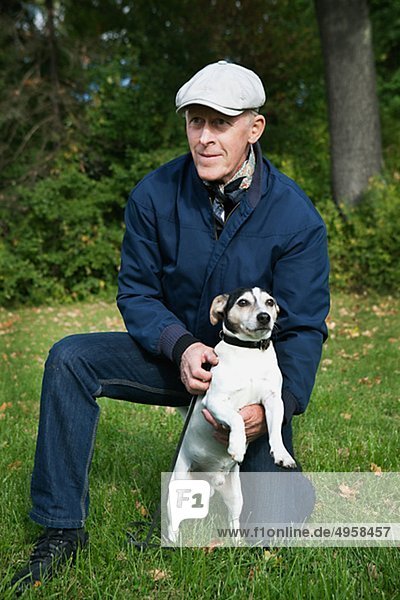 Senior man kneeling on grass with dog