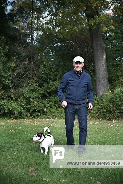 Senior man standing on grass with dog