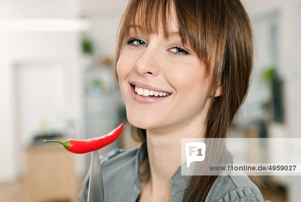 Woman holding red chilli with knife