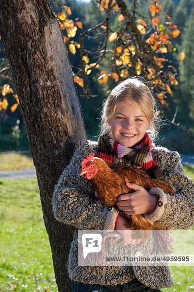 Österreich  Salzburg  Flachau  Mädchen mit Henne im Bauerngarten  lächelnd