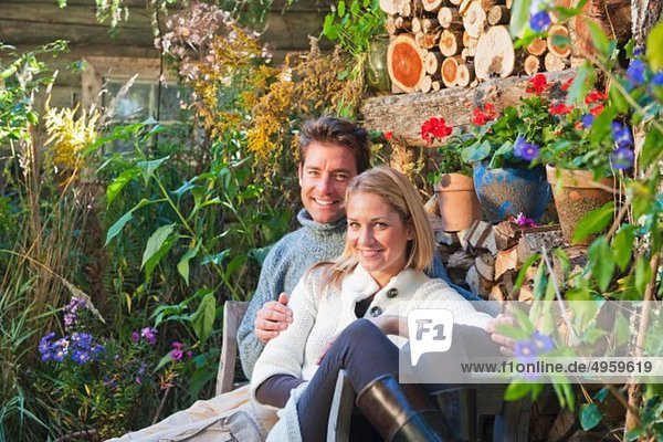 Austria  Salzburg  Flachau  Man and woman sitting on bench in garden of farm  smiling  portrait