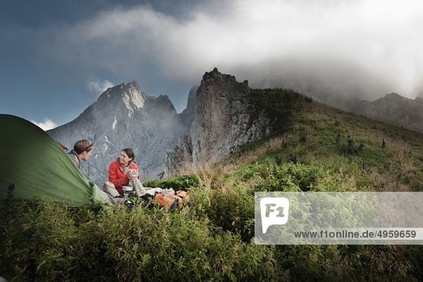 Österreich  Salzburger Land  Filzmoos  Paar sitzend neben Zelt auf Bergen