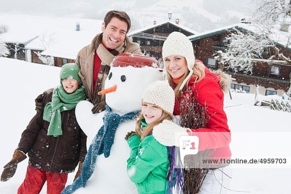 Österreich  Salzburg  Hüttau  Familie mit Schneemann  lächelnd
