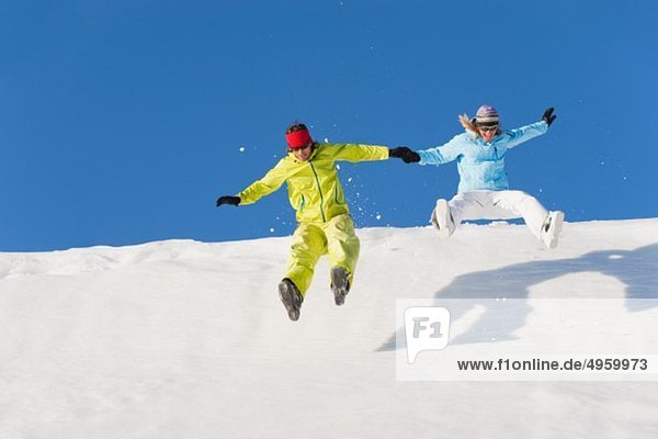 Italy  Trentino-Alto Adige  Alto Adige  Bolzano  Seiser Alm  Man and woman jumping on snow