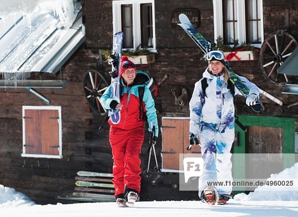 Österreich  Kleinwalsertal  Frauen mit Ski auf den Schultern bei der Berghütte
