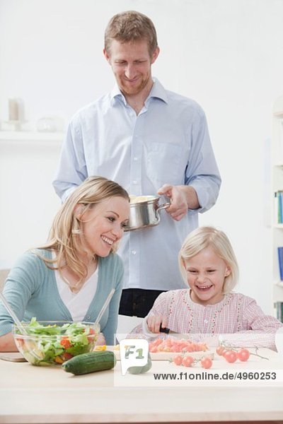 Deutschland  Bayern  München  Eltern und Tochter bei der Zubereitung des Essens  lächelnd