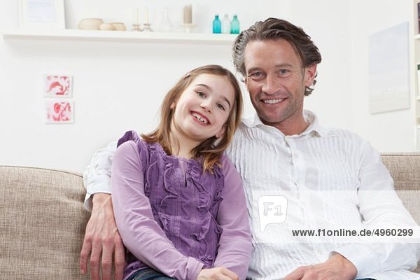 Germany  Bavaria  Munich  Father with daughter sitting on couch  smiling  portrait